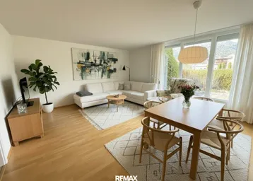 Heller, offener Wohn- und Essbereich mit Parkettboden, bequemen Sofas und großem Esstisch.