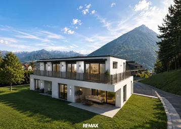 Moderne Villa mit Balkonen, Rasenfläche und beeindruckendem Bergblick unter blauem Himmel.