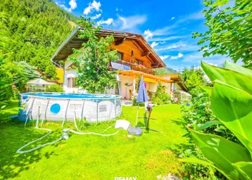 Großzügiger Gartenbereich mit Aufstellpool, umgeben von grüner Natur und Bergen.