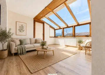 Helles Wohnzimmer mit großen Dachfenstern, Holzbalken und Bergblick, ausgestattet mit gemütlichen Möbeln.