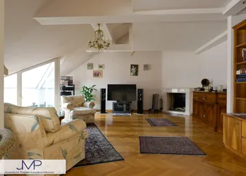 Geräumiges Wohnzimmer mit Parkettboden, Kamin und Dachschrägen, ideal für gemütliche Abende.