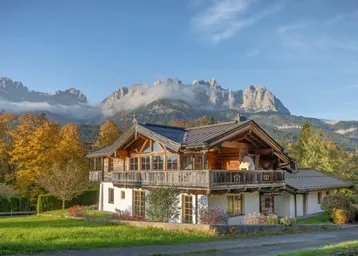 Charmantes Chalet mit traditioneller Holzarchitektur, umgeben von herbstlicher Natur und majestätischem Bergblick.