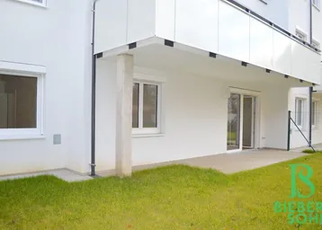 Erdgeschoss-Terrasse mit direktem Zugang zum Gartenbereich und Blick auf die moderne Fassade.