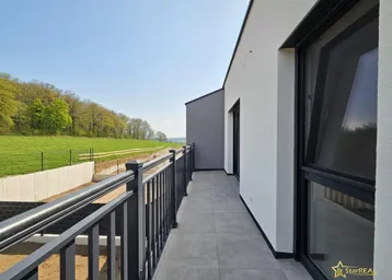 Geräumiger Balkon des Neubaus mit Blick auf grüne Felder und die umliegende Natur.