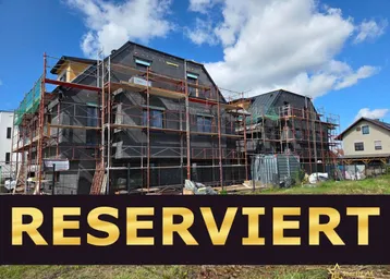 Neubauprojekt im Bau mit Gerüst und sichtbarer Dämmung unter blauem Himmel.