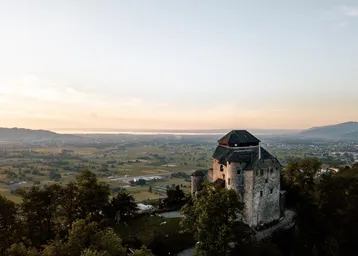 Historisches Gebäude auf einem Hügel mit weitem Blick über die Landschaft bei Sonnenuntergang.