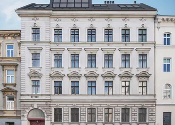 Historisches Gebäude mit klassischer Fassade und modernem Dachausbau in städtischer Umgebung.