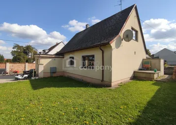 Seitenansicht eines Einfamilienhauses mit Rasenfläche und blauem Himmel an einem sonnigen Tag.