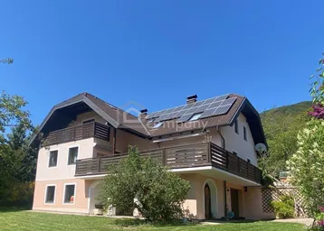 Großes Einfamilienhaus mit mehreren Balkonen, Photovoltaikanlage auf dem Dach und Garten.