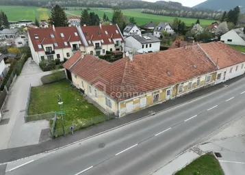Luftaufnahme eines ländlichen Anwesens mit mehreren Gebäuden und angrenzender Straße.