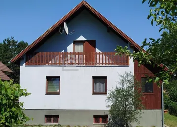 Frontansicht eines Einfamilienhauses mit Satteldach, Balkon und weißer Fassade.