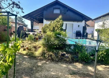 Großzügiger Gartenbereich mit Pool und viel Grün, umgeben von Bäumen und Sträuchern.