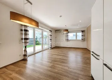 Helles, offenes Wohnzimmer mit Laminatboden und großem Zugang zum Gartenbereich.