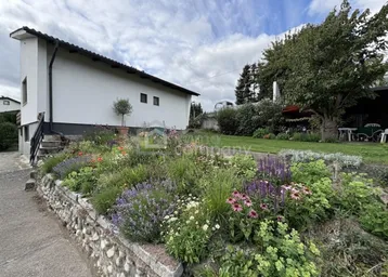 Gepflegter Gartenbereich mit vielfältigen Blumenbeeten und Blick auf das Wohnhaus.
