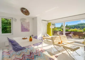 Helles Wohn- und Esszimmer mit modernen Möbeln, farbigem Teppich und Zugang zur Terrasse.