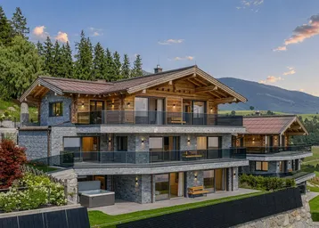 Luxuriöses Chalet mit moderner Architektur, Stein- und Holzfassade, umgeben von alpiner Landschaft.