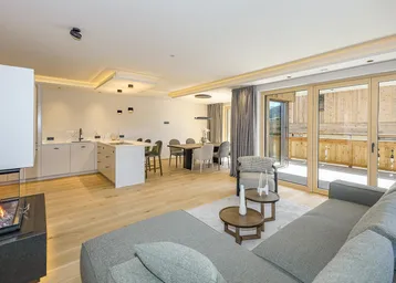 Heller Wohnbereich mit Kamin, Holzboden und Zugang zu einem großen Balkon.