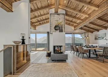 Geräumiger Wohn- und Essbereich mit Holzbalkendecke, Kamin und Panoramablick auf die Berge.