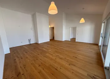 Geräumiger, heller Wohnbereich mit neuem Eichenparkettboden und hohen Decken, bereit für die individuelle Gestaltung.