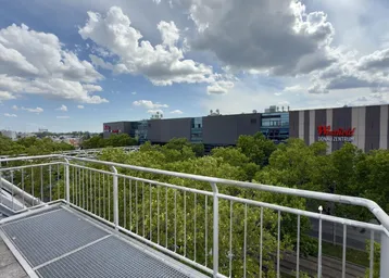 Dachterrasse mit Blick auf das Donau Zentrum und die umliegende Stadtlandschaft unter einem bewölkten Himmel.