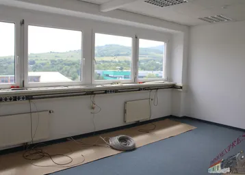 Helles, leeres Büro mit großen Fenstern, die einen weiten Blick ins Grüne und auf die Umgebung bieten.
