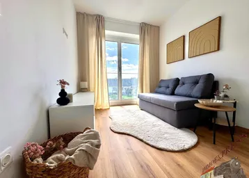 Heller Wohnbereich mit bequemer Couch, Holzboden und Zugang zu einem französischen Balkon.