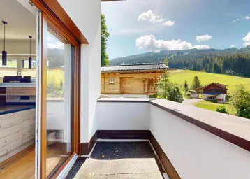 Heller Balkon mit Holzboden und weitem Blick auf die grüne Berglandschaft.