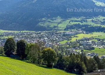 Weitläufige Landschaft mit grünen Hügeln und einem Dorf im Tal.