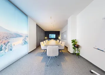 Moderner Konferenzraum mit großem Tisch, bequemen Stühlen und einer beeindruckenden Winterlandschaft als Wandbild.