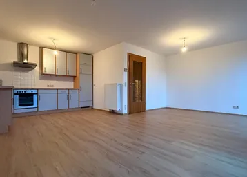 Offener Wohn- und Essbereich mit integrierter Küche und hellem Laminatboden in gutem Zustand.