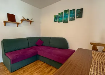 Gemütlicher Wohnbereich mit Ecksofa, Holztisch und dekorativen Bildern an der Wand.