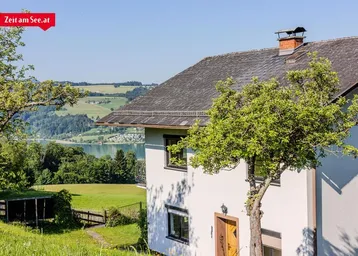 Hausfassade mit Blick auf den See und die umliegende grüne Landschaft.