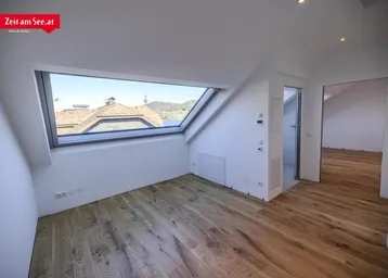 Helles Dachzimmer mit Holzboden und großem Dachfenster bietet Seeblick und Bergblick.