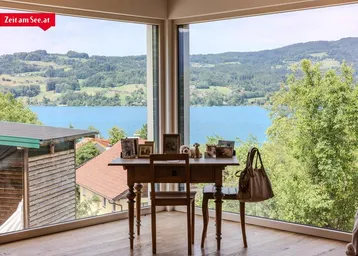 Helles Arbeitszimmer mit großen Fenstern und atemberaubendem Blick auf den See und die umliegende Landschaft.