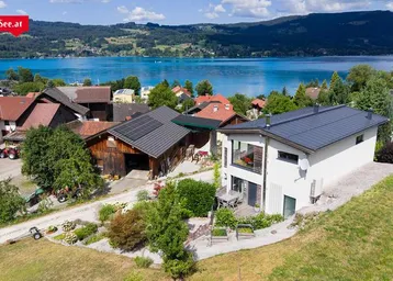 Luftaufnahme des modernen Hauses mit Solarpaneelen und Seeblick in ländlicher Umgebung.