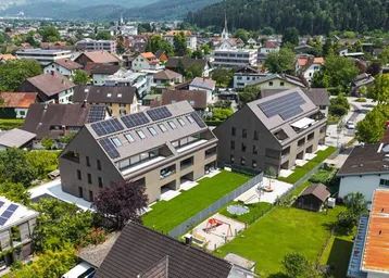 Luftaufnahme von zwei modernen Gebäuden mit Solaranlagen, umgeben von Wohnsiedlung und Grünflächen.