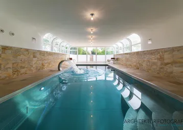 Innenpool mit Wasserspeier und breiter Treppe, umgeben von hellen Steinwänden.