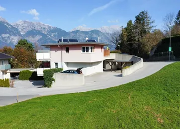 Wohnhaus mit moderner Architektur, Photovoltaikanlage auf dem Dach und beeindruckendem Bergblick.