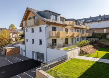 Modernes Mehrfamilienhaus mit Balkonen, Terrassen, Tiefgarage und gepflegten Grünflächen in sonniger Lage.