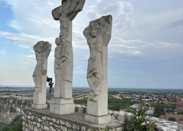 Historische Steinstatuen auf einer Anhöhe mit weitem Blick über die Landschaft.