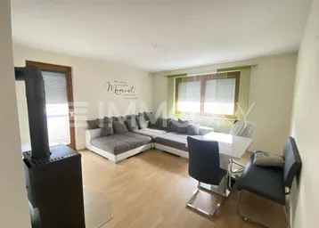 Heller Wohn- und Essbereich mit gemütlichem Ecksofa, Esstisch und einem Holzofen für zusätzliche Wärme.