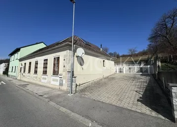 Altes Gebäude mit heller Fassade und gepflasterter Einfahrt unter blauem Himmel.