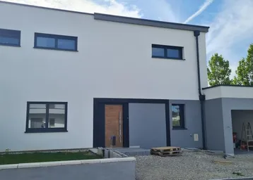Moderne Neubaufassade in Weiß und Grau mit schwarzen Fenstern und Holztür, inklusive Carport.
