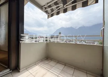 Balkon mit Markise und weitem Blick auf die Berge und die Stadt.