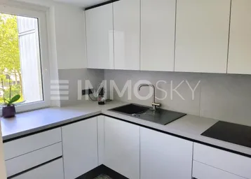 Moderne Einbauküche mit weißen Hochglanzfronten, Spüle und Induktionskochfeld.