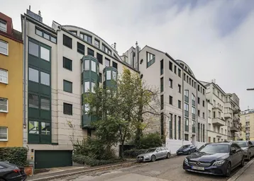 Moderne Wohngebäude-Fassade mit markanten grünen Erkern und Garagenzufahrt an einer Straße.