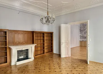 Elegantes Zimmer mit Kamin, Einbauregalen und klassischem Fischgrätparkett.