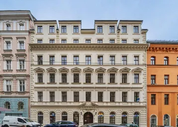 Historisches Gebäude mit klassischer Fassade und vielen Fenstern an einer Stadtstraße.