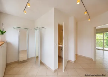 Heller Flur mit Fliesenboden, modernen Deckenspots und Zugang zu weiteren Räumen.