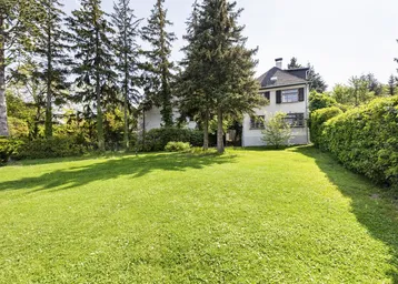 Großzügiger Gartenbereich mit weitläufiger Rasenfläche und altem Baumbestand vor dem Haus.